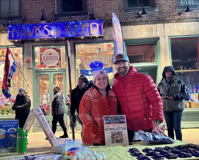 Smiling people stand behind an activity table at Winter Carnival 2024